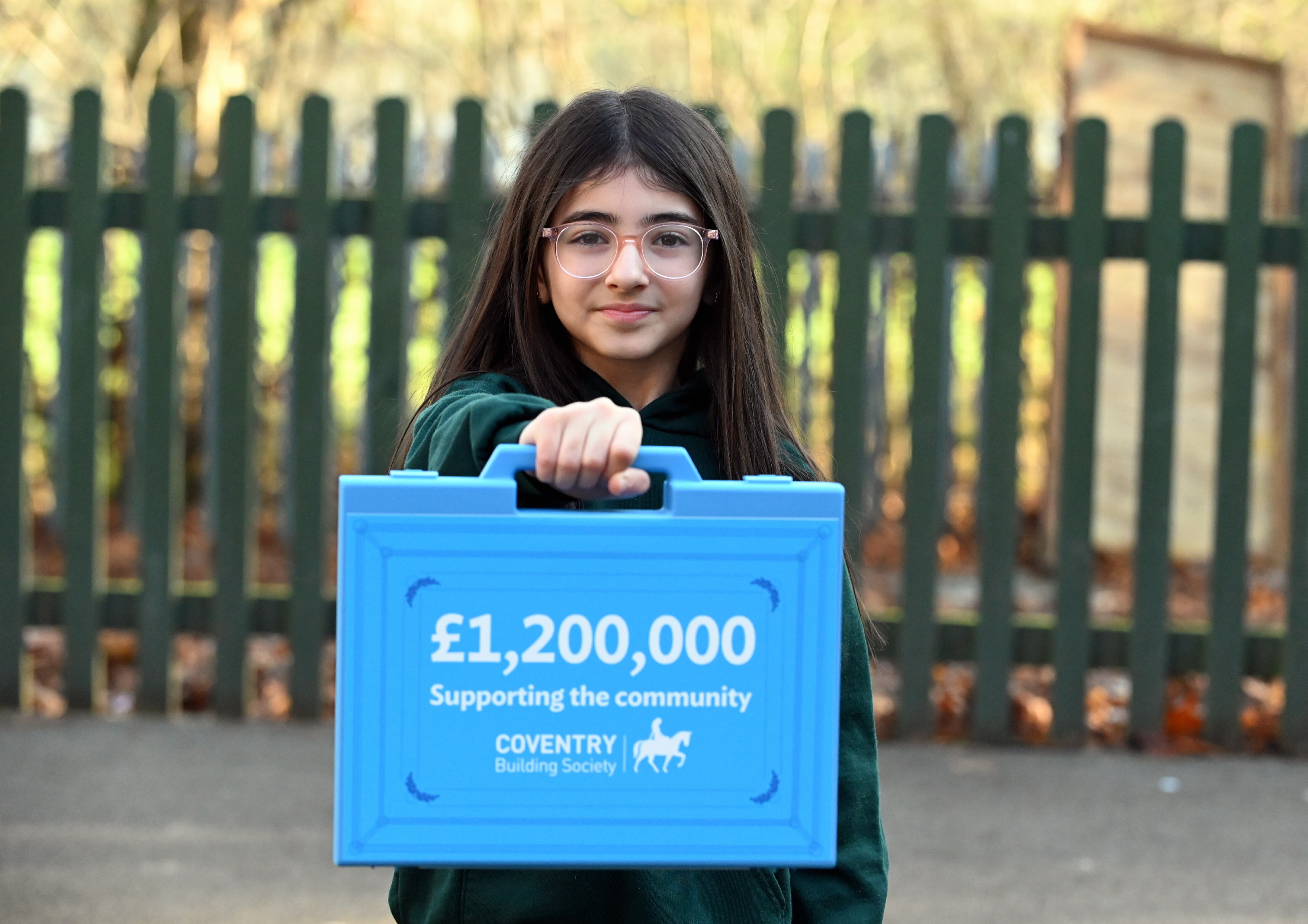 Image of a girl holding a blue briefcase with £1.2m written on it