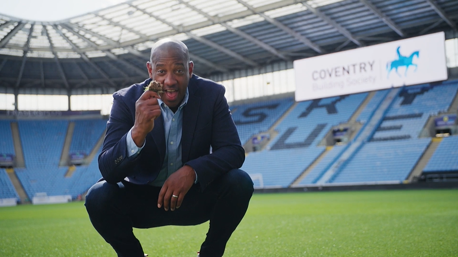 Dion kneeling on the CBS arena pitch holding some turf