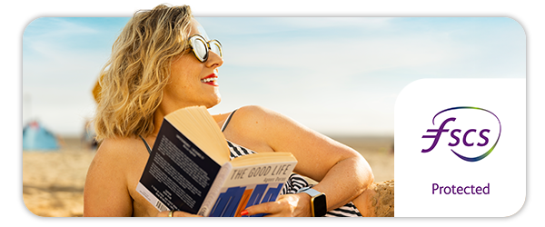 Close up image of a woman lying on the beach reading 